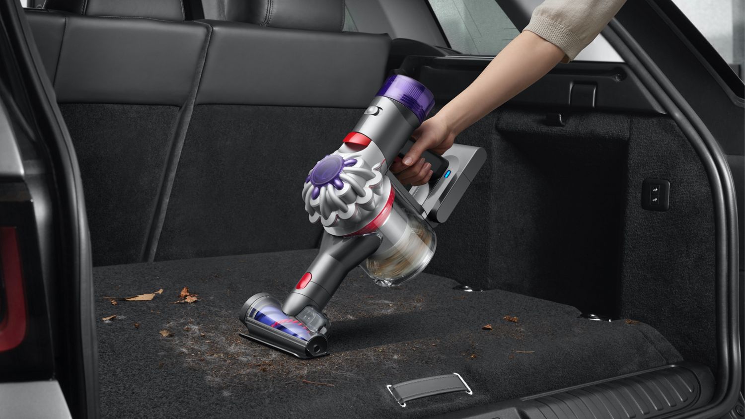 Dyson V8 in handheld mode cleaning the trunk of a car