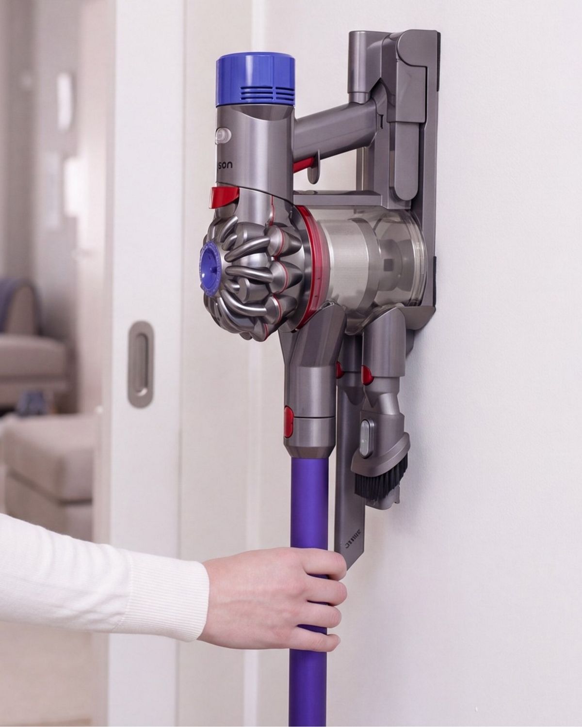 The Dyson V8 vacuum is being returned to its charging dock.