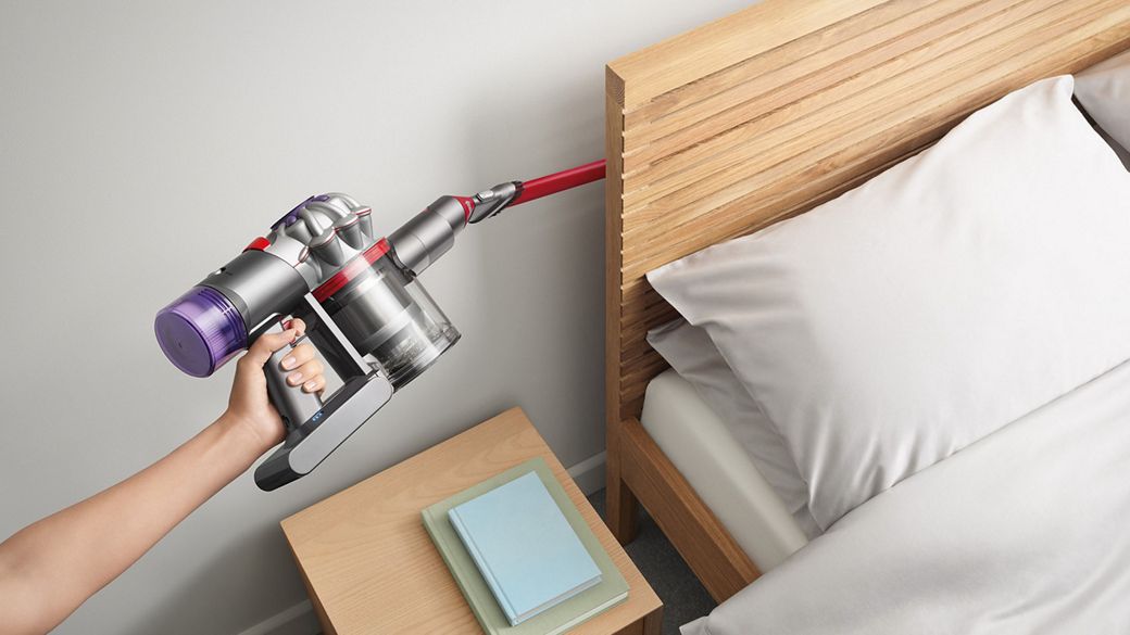 Dyson V8 Focus Clean handheld vacuum used to clean behind a bed.