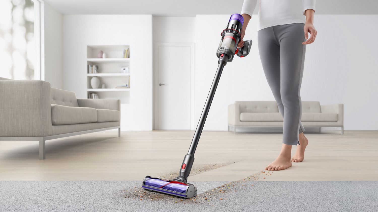 A person uses the Dyson V9 vacuum to clean hard floors and carpet in a home with the Motorbar cleaner head.