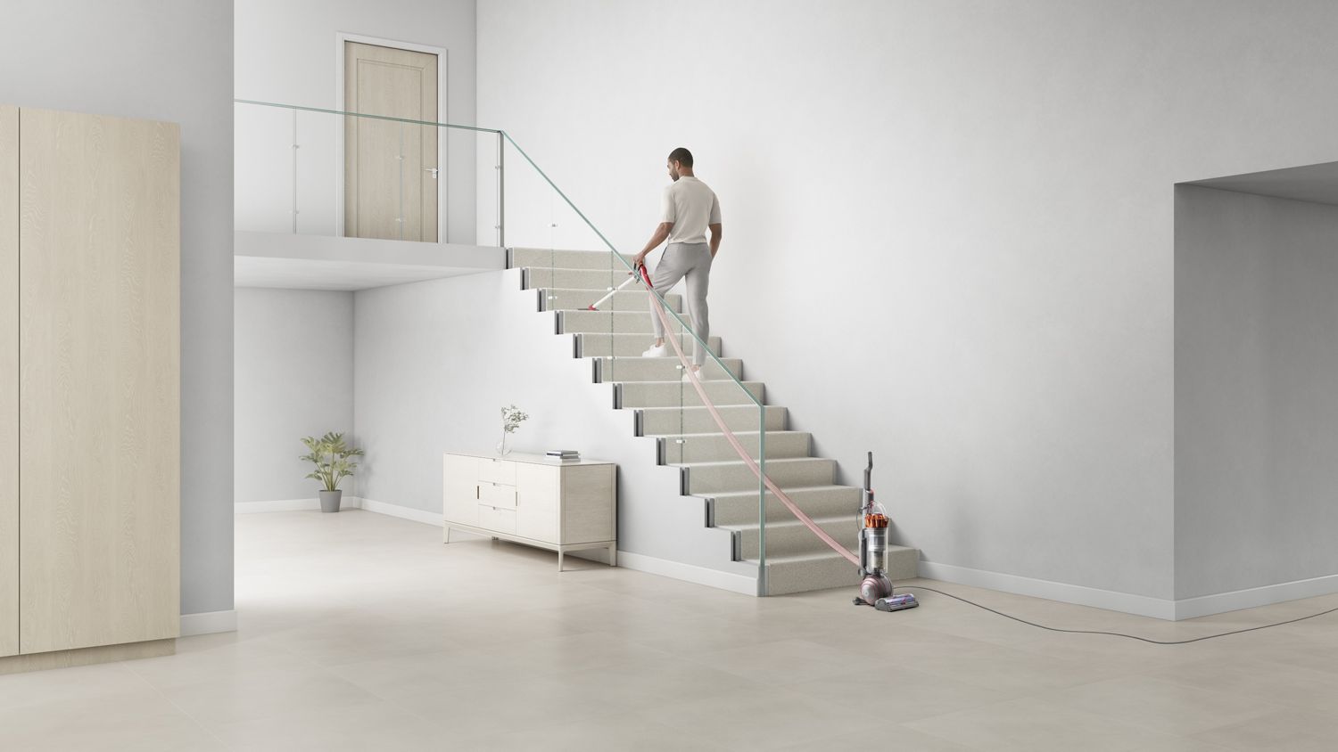 Dyson Ball Animal vacuum cleaner reaching up stairs with an extra-long hose and cord.