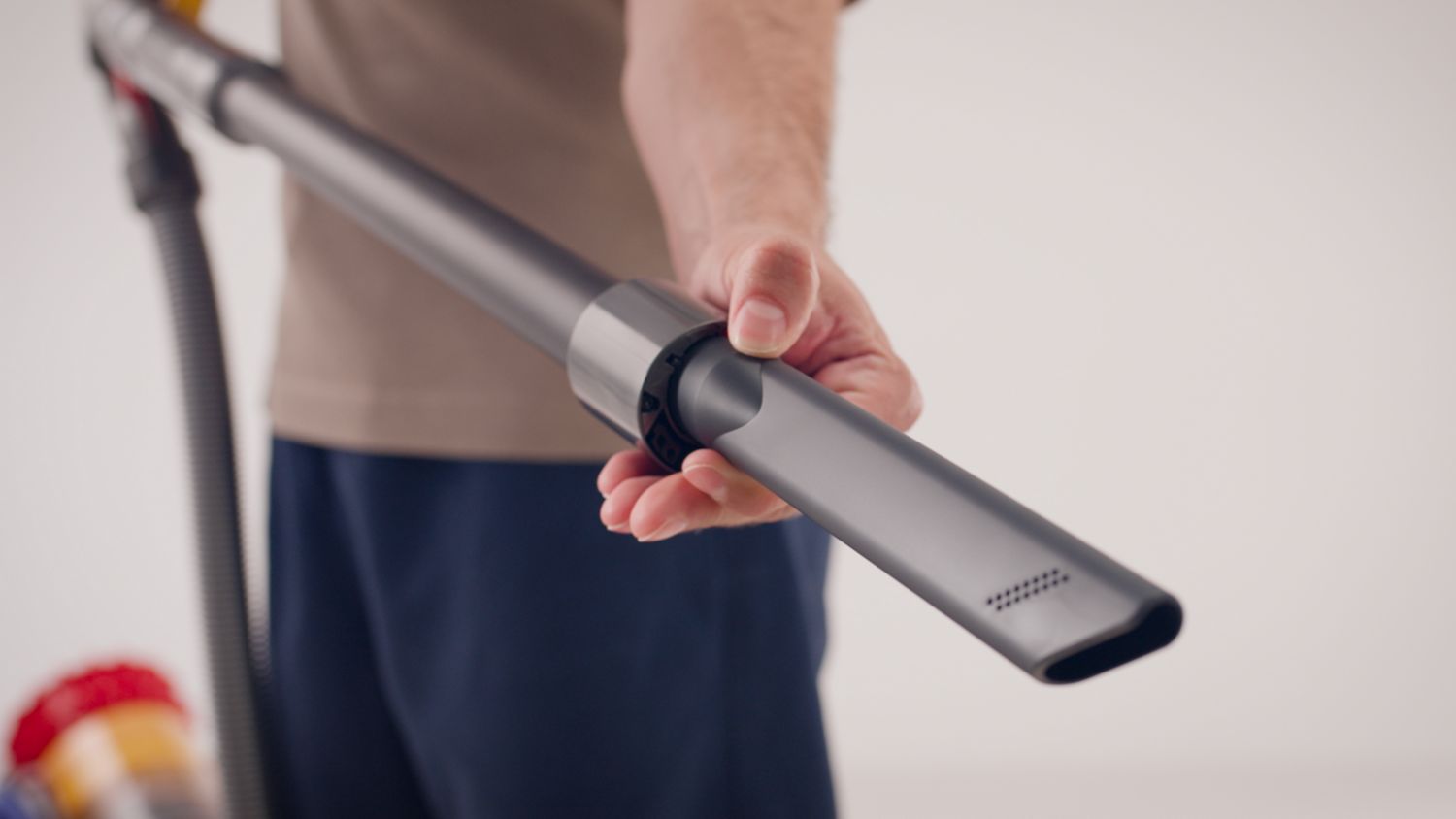 A crevice tool is removed from the wand of a Dyson corded vacuum.