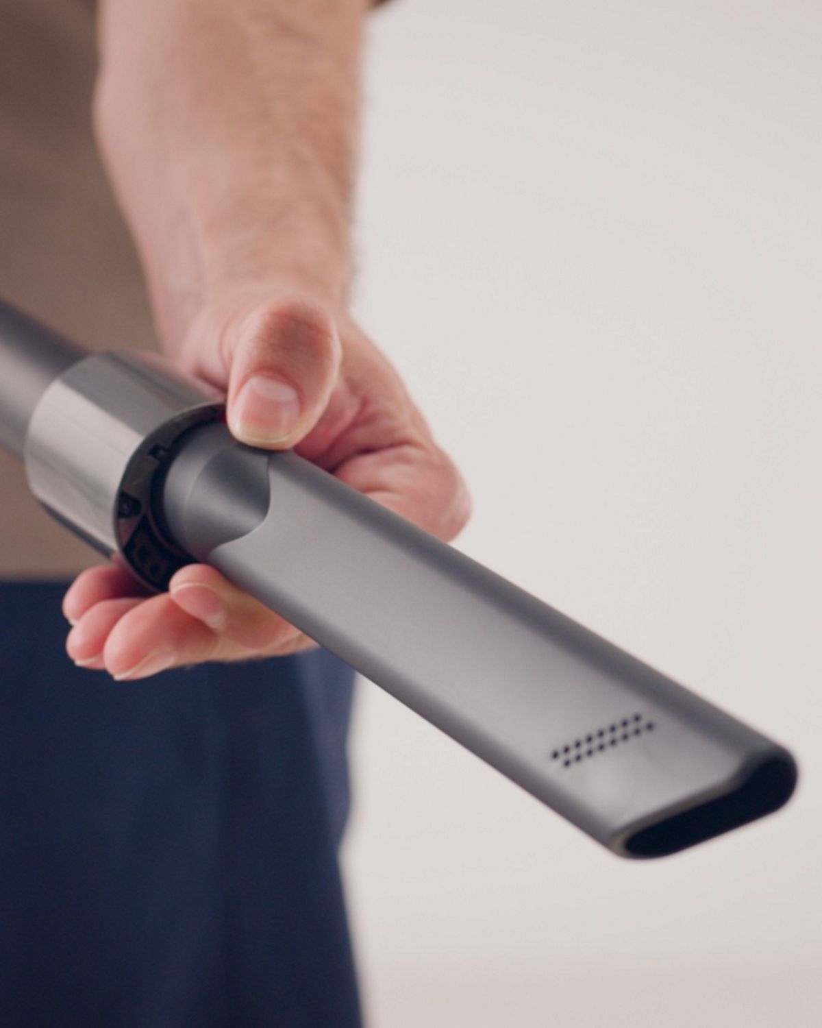 A crevice tool is removed from the wand of a Dyson corded vacuum.