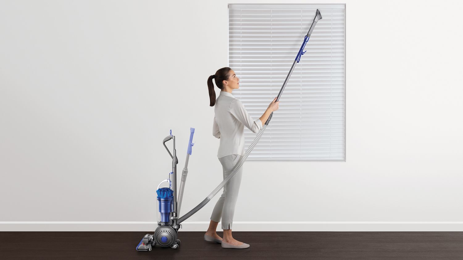 Dyson Ball Total Clean upright vacuum cleaner being used to clean household blinds. 