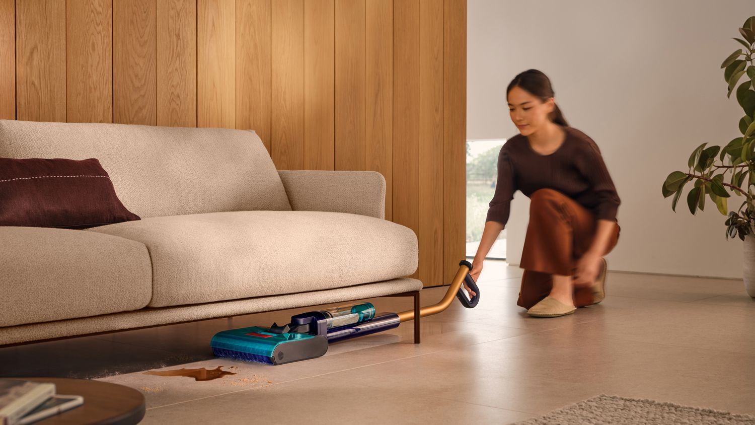 The Dyson Clean+Wash Hygiene hard floor cleaner washing the floor under a sofa.