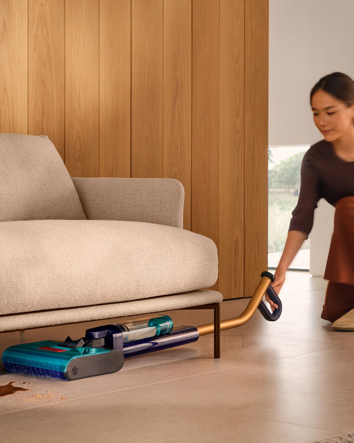 The Dyson Clean+Wash Hygiene hard floor cleaner washing the floor under a sofa.