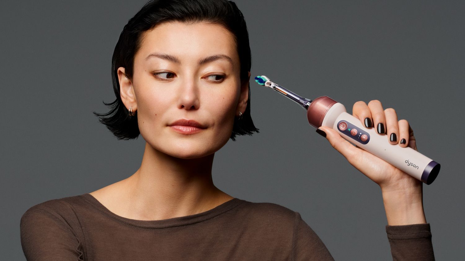 Model holds the Dyson Camerajet toothbrush.