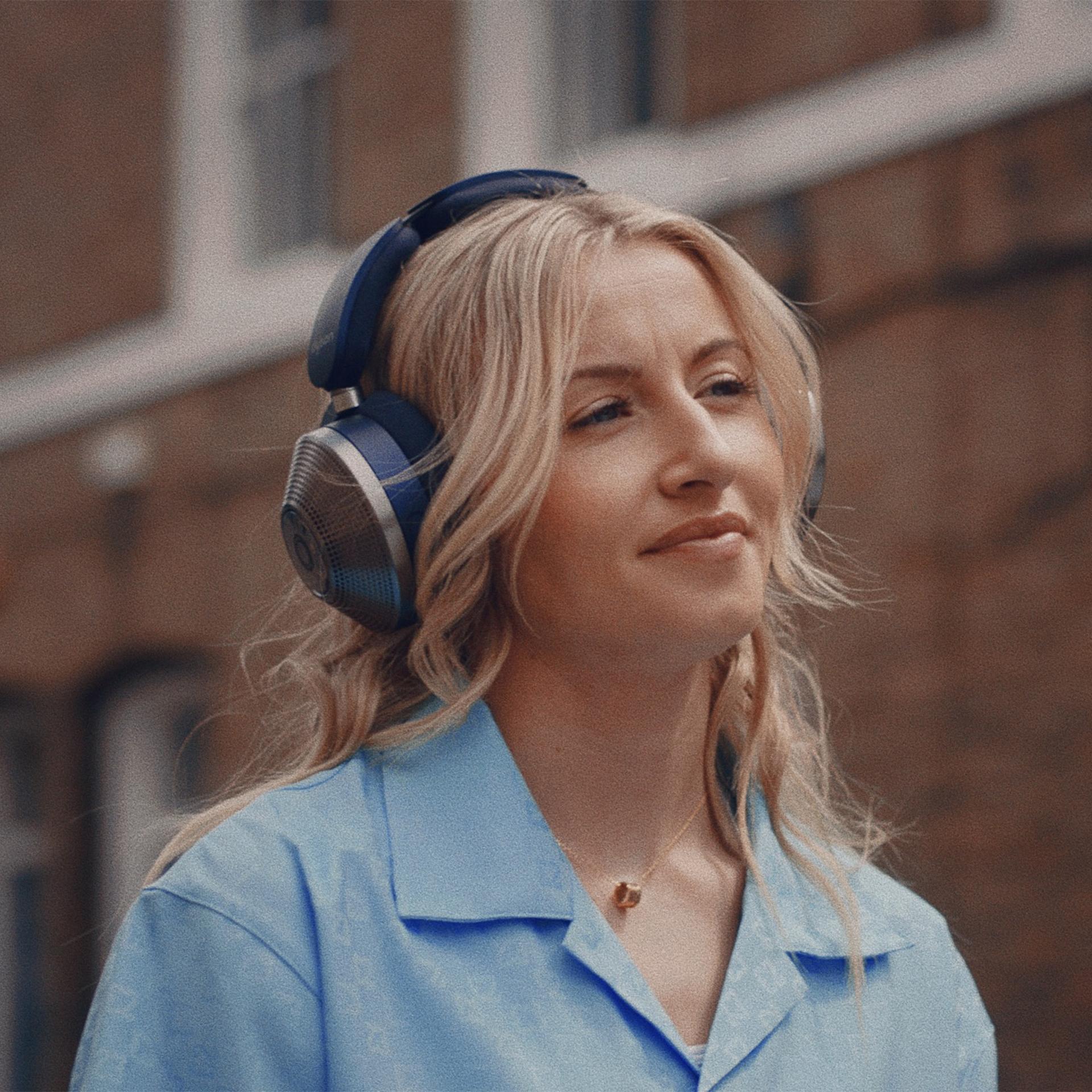 Woman wearing Dyson headphones in her bedroom