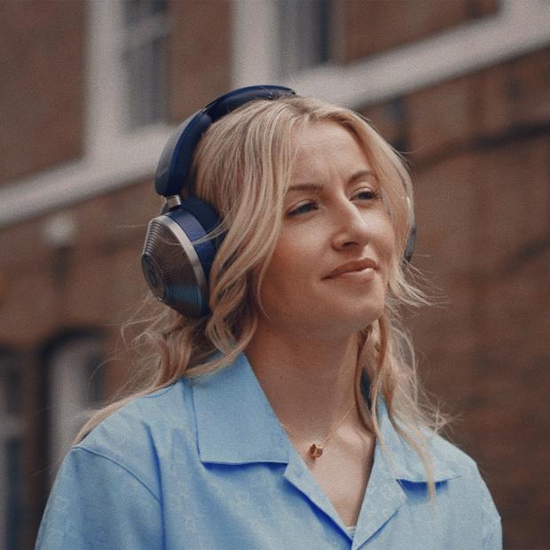Woman wearing Dyson headphones in her bedroom