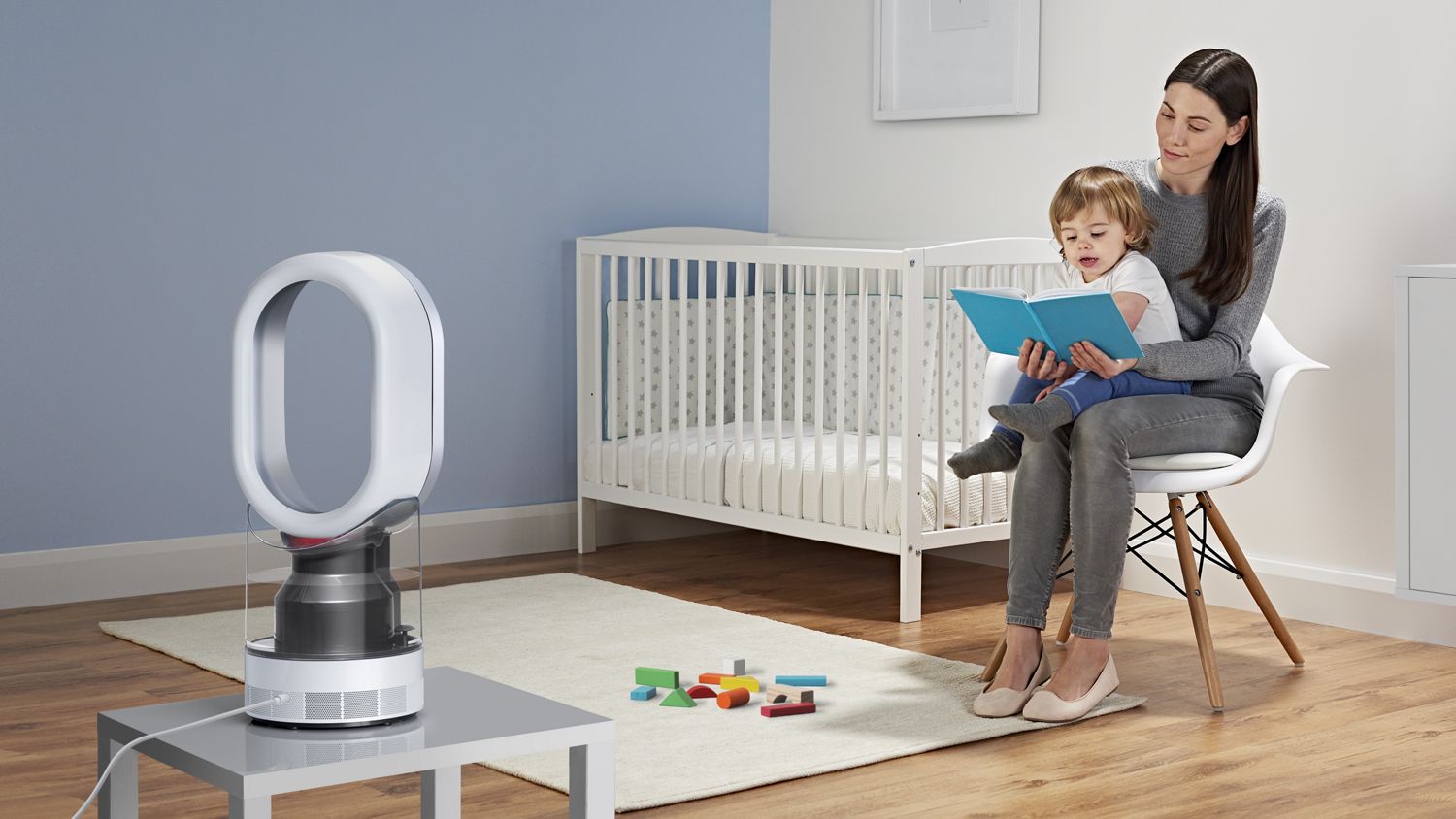 Une femme lit une histoire à un enfant assis devant un humidificateur Dyson.
