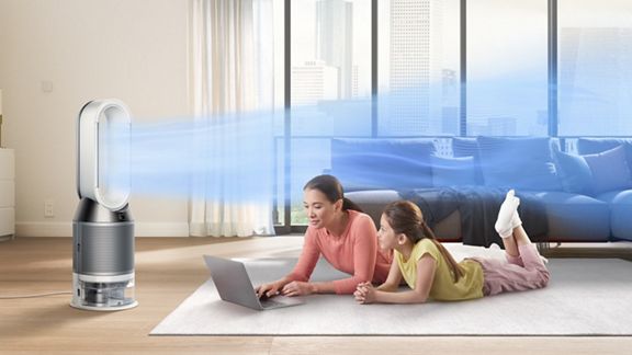 Une femme et sa fille sont installées devant un ordinateur portable pendant que le Dyson Pure Humidify+Cool rafraîchit la pièce. 
