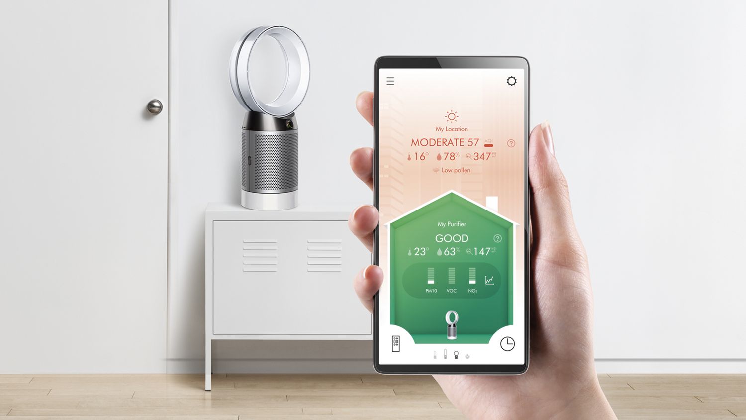 A user holding up the Dyson Link App to control their Dyson Pure Cool purifier fan in the background. 
