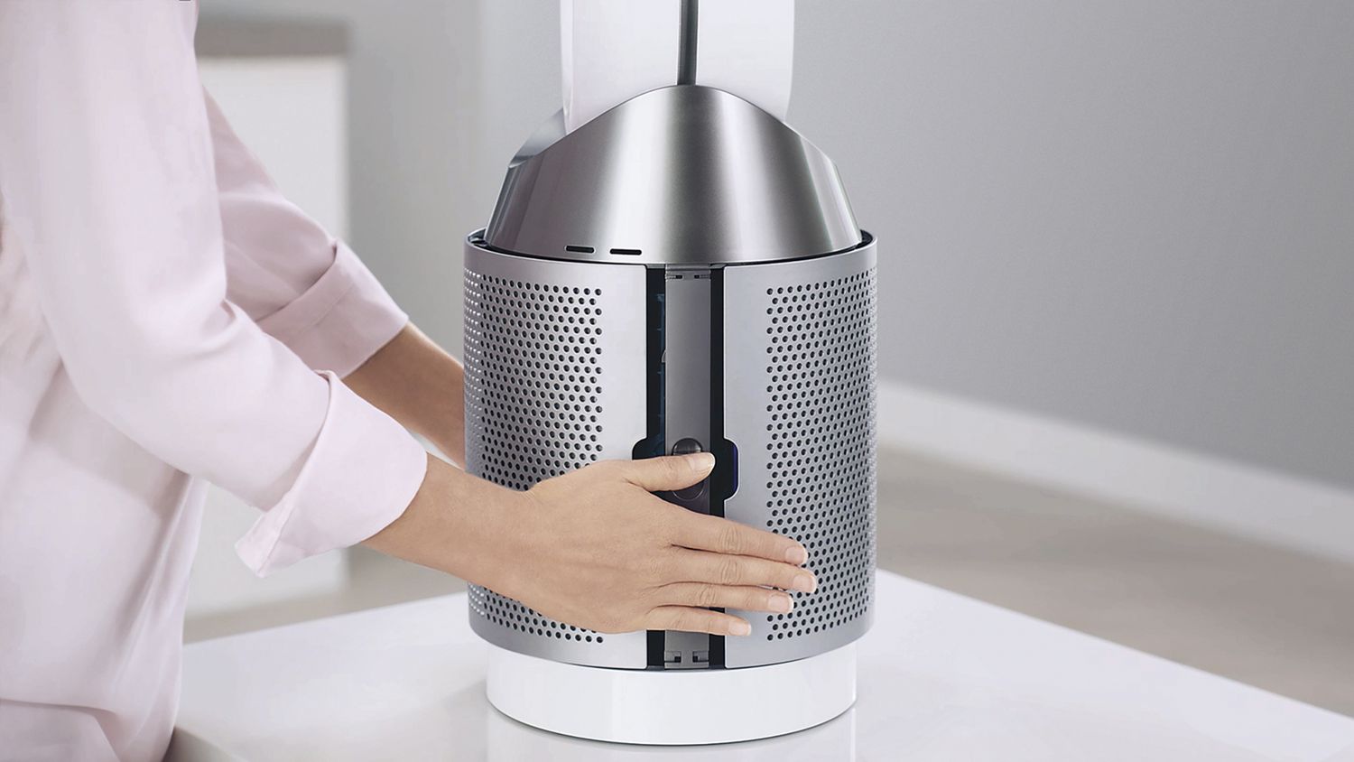 Utilisateur appuyant sur les côtés du boîtier du filtre d’un Dyson Pure Cool pour en dégager le filtre interne.  