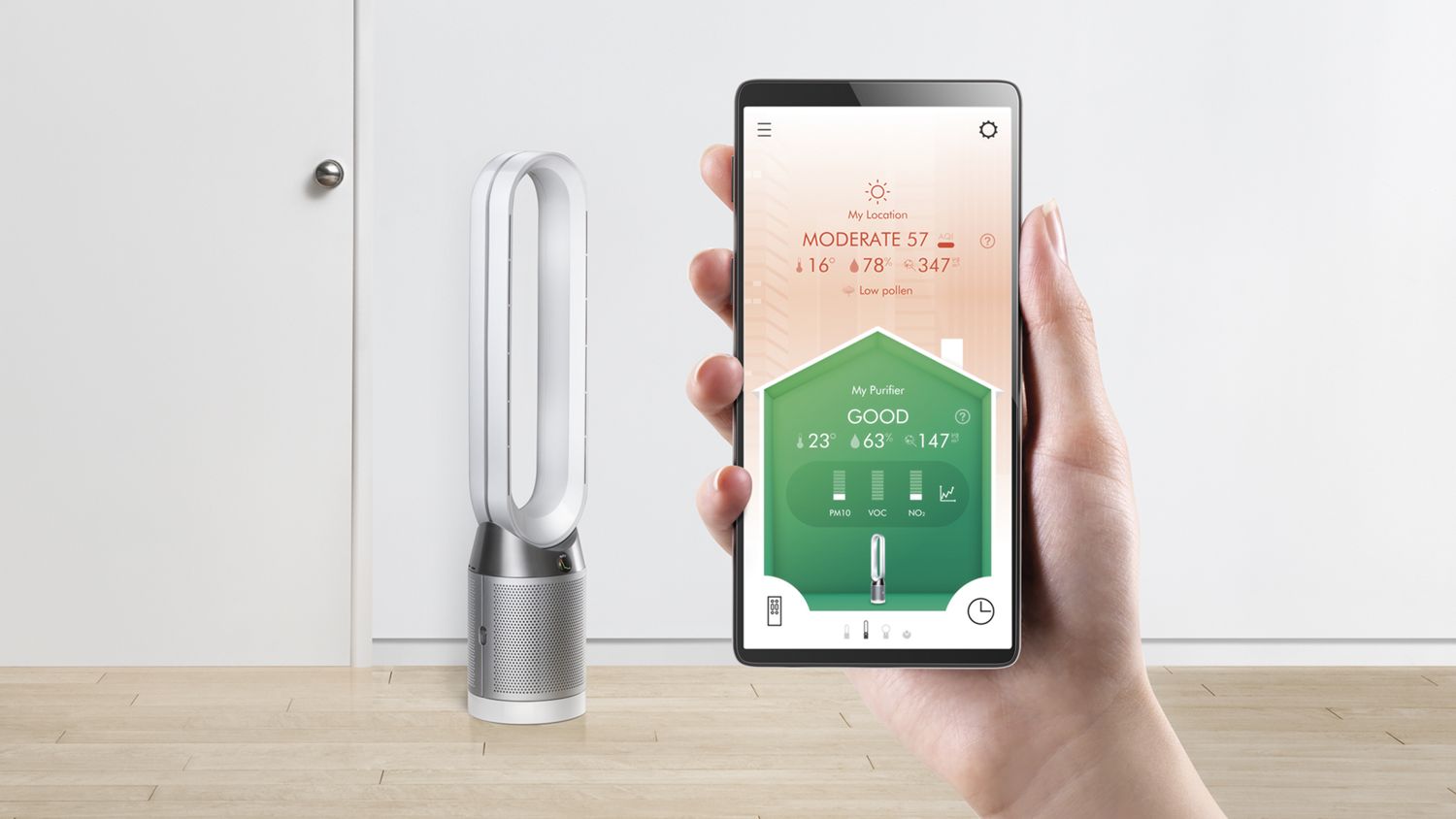 A user holding up the Dyson Link App to control their Dyson Pure Cool purifier fan in the background. 