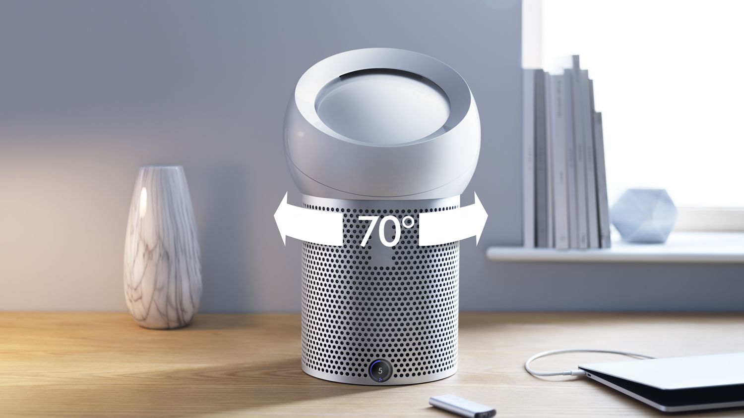 Ventilateur purificateur personnel Dyson Pure Cool Me posé au  milieu d’un bureau; l’image est annotée d’un symbole 70 degrés montrant l’oscillation de gauche à droite. 