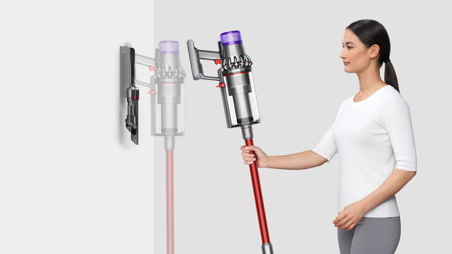 Woman placing Dyson Outsize+ vacuum into wall charging dock