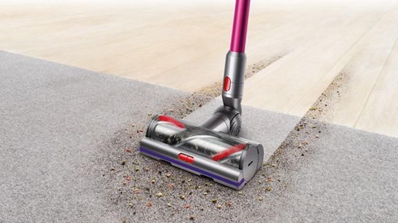 Tête d’aspirateur V11 à couple élevé ramassant des débris sur du tapis.
