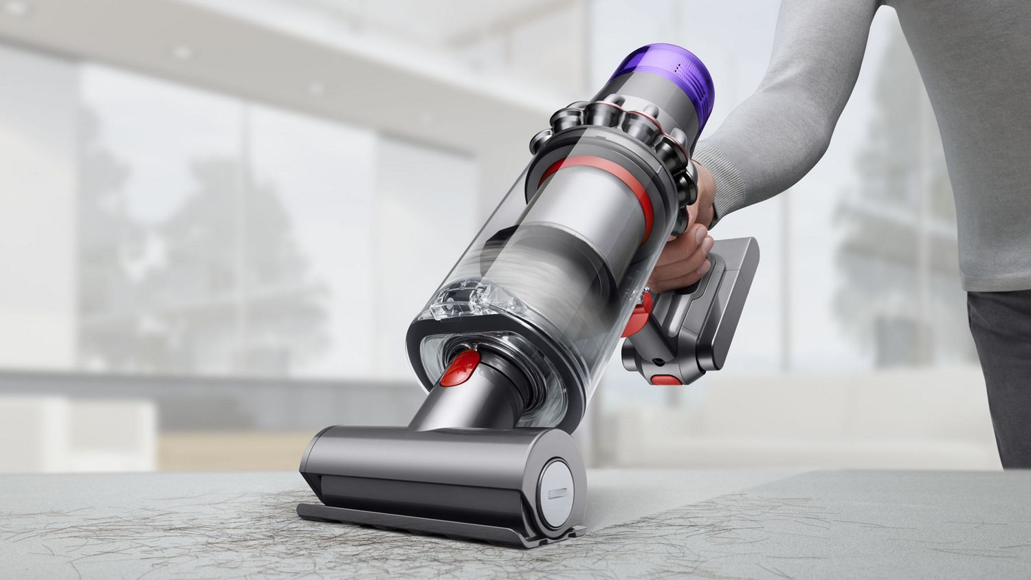 Aspirateur sans fil Dyson V11 Torque Drive utilisé en mode portatif pour ramasser des débris sur un meuble rembourré.