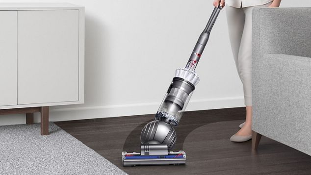 Dyson Slim Ball upright vacuum cleaner manoeuvring around furniture to clean floor.