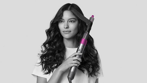 Femme bouclant ses cheveux à l’aide du séchoir coiffant Dyson Airwrap.