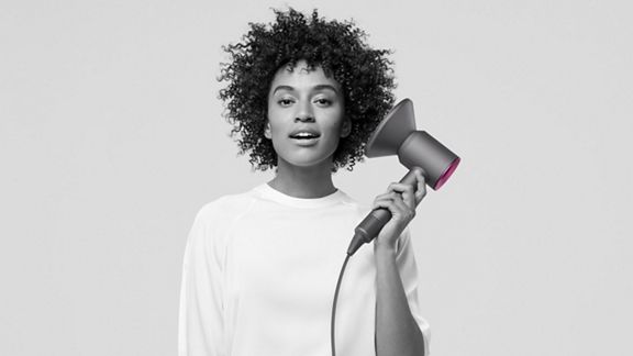 Woman holding Dyson Supersonic hair dryer with diffuser attached.