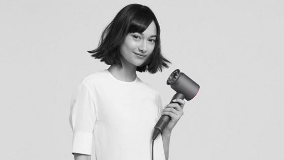 Woman holding Dyson Supersonic hair dryer.