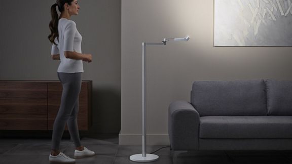 Femme se tenant debout pendant que la lampe Dyson Lightcycle Morph éclaire une œuvre d’art.
