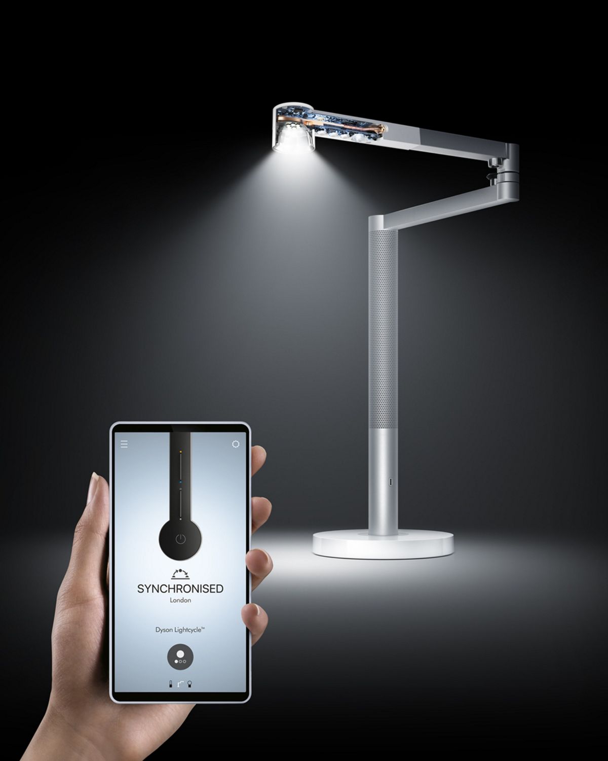 Dyson lightcycle morph lights with inner technology exposed. An image of planet earth sits next to it as a hand operates the dyson link app on a smartphone. 