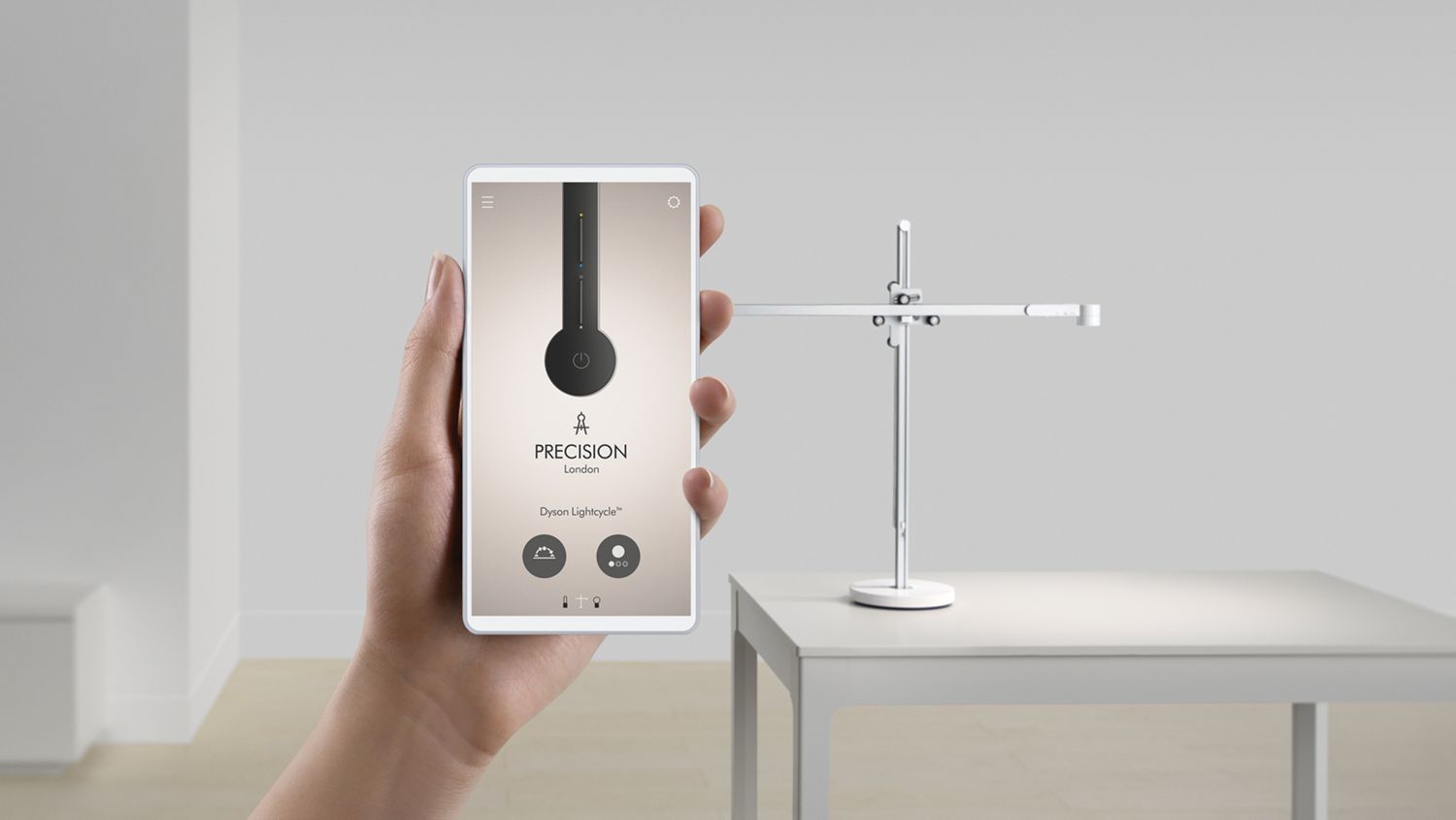 Une main tient un téléphone intelligent affichant l’application Dyson Link; à l’arrière-plan, une lampe Dyson Lightcycle. 