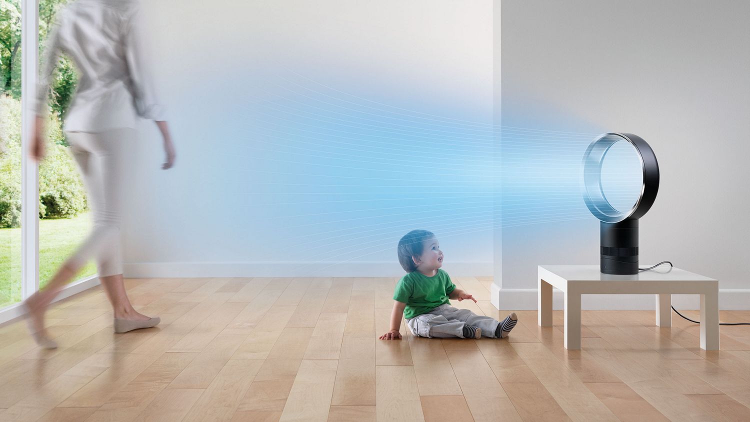 Une famille assise sur un canapé, tandis qu’un Dyson Cool projette de l’air frais dans sa direction et dans toute la pièce.