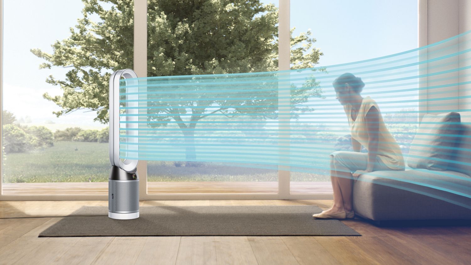 Eine Frau sitzt auf einem Sofa in einem blauen Luftstrom, der die vom Dyson Pure Cool™ Luftreiniger verteilte kühle, gereinigte Luft darstellt. Draußen ist es sonnig. 