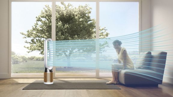 Persona sul divano e un flusso blu mostra aria purificata, proiettata dal purificatore ventilatore Dyson Cool Cryptomic