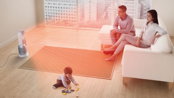 Il purificatore ventilatore Dyson Pure Cool si trova al centro di un salotto con una famiglia, mentre un bambino gioca.I flussi rossi provenienti dall'anello della macchina mostrano la proiezione di aria calda e purificata nella stanza.