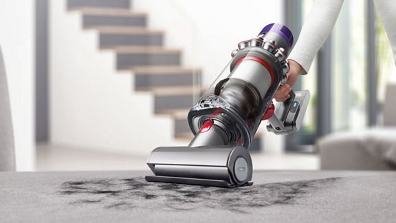 Aspirador sem fios Dyson V10 Absolute em modo de mão limpa a sujidade dos estofos.