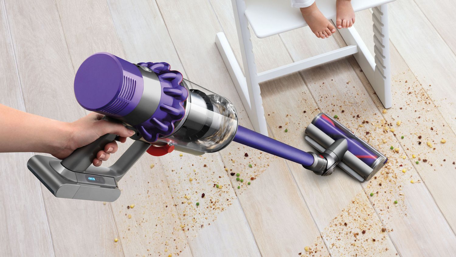 Woman using Dyson V10 Animal cordless vacuum cleaner to vacuum hard floor.
