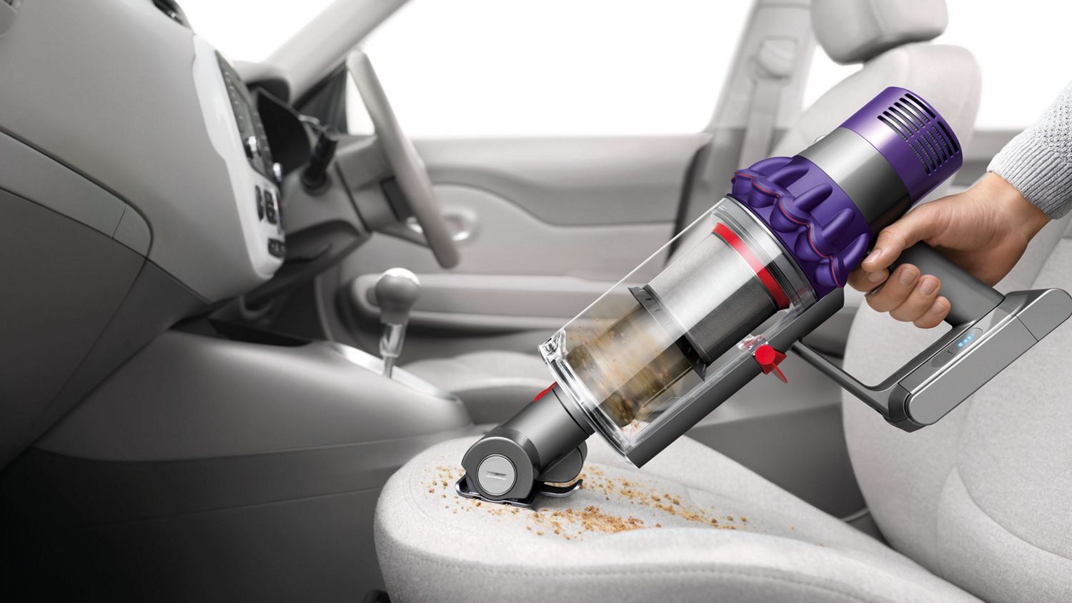 Dyson V10 Animal cordless vacuum in handheld mode picking up debris from carpet.