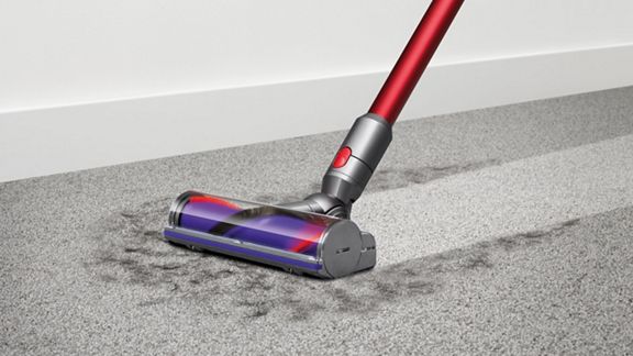 Dyson V10™ Motorhead  kabelloser Staubsauger nimmt Schmutz von einem Hartboden auf.