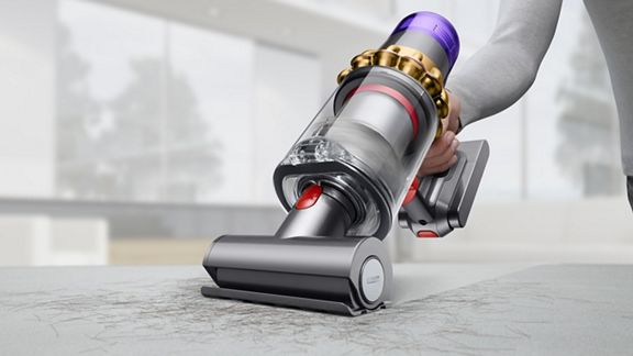Un aspirateur sans fil Dyson V11 Absolute Pro utilisé en tant qu’aspirateur à main pour nettoyer des débris sur des tissus d’ameublement.