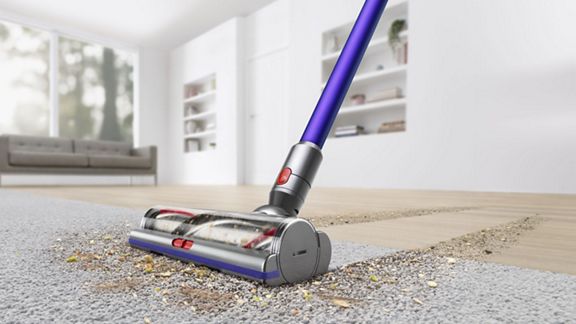 Dyson V11™ Torque Drive Extra kabelloser Staubsauger entfernt Schmutz von einem Teppichboden.