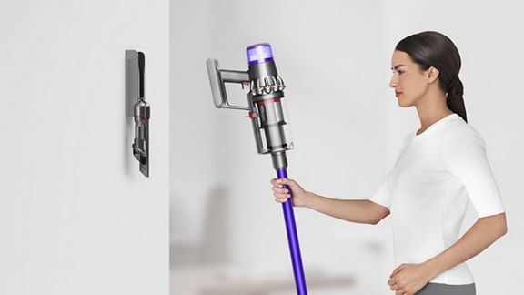 Dyson V11™ Torque Drive Extra kabelloser Staubsauger wird an die Ladestation angeschlossen.