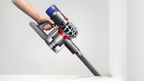 Ein Dyson V8™ Motorhead kabelloser Staubsauger wird im Handheld-Modus mit aufgesetzter Fugendüse verwendet, um einen schwierig zu erreichenden Bereich zu reinigen.