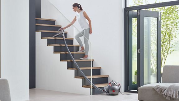 Dyson Cinetic Big Ball™ Absolute 2 Staubsauger wird verwendet, um Schmutz von den Treppen zu entfernen.