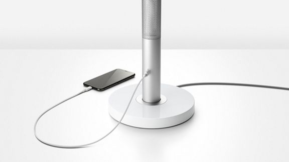 Ein Mobiltelefon, das an die Ladestation an der Basis der Dyson Solarcycle Morph™ Tischleuchte angeschlossen ist. 