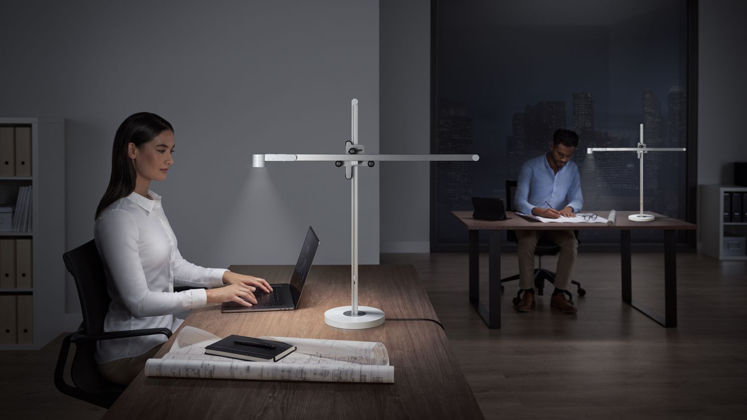 Une femme travaillant sur son ordinateur portable à un bureau, avec la lampe de bureau Dyson Solarcycle éclairant son espace de travail. 
