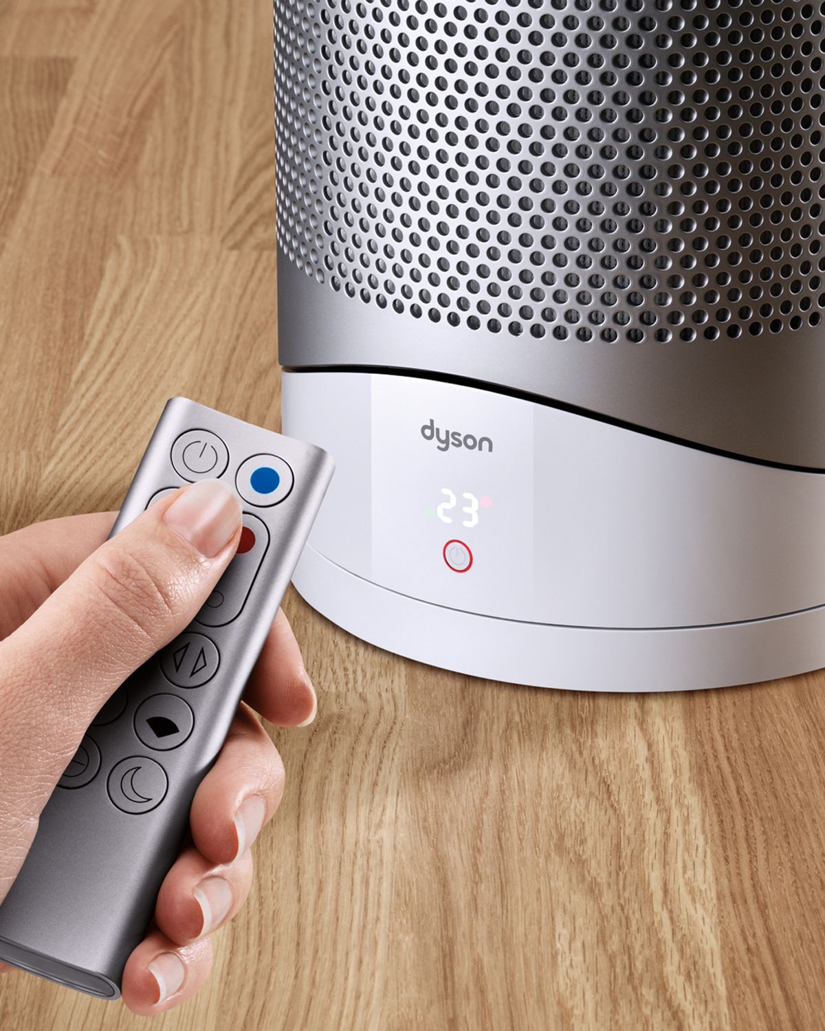 A user controls the Dyson Pure Hot+Cool purifier fan heater with their remote. 
