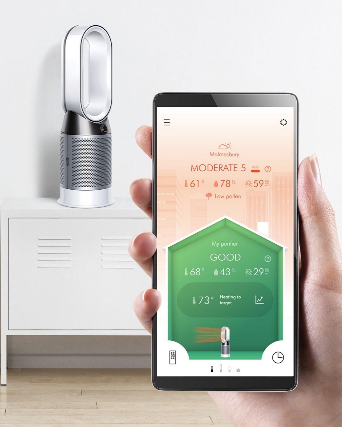 A Dyson Hot + Cool purifier rests on a table as a smartphone shows the Dyson link app.