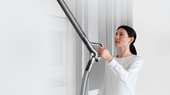 Woman using extendable hose to clean hard to reach area. 