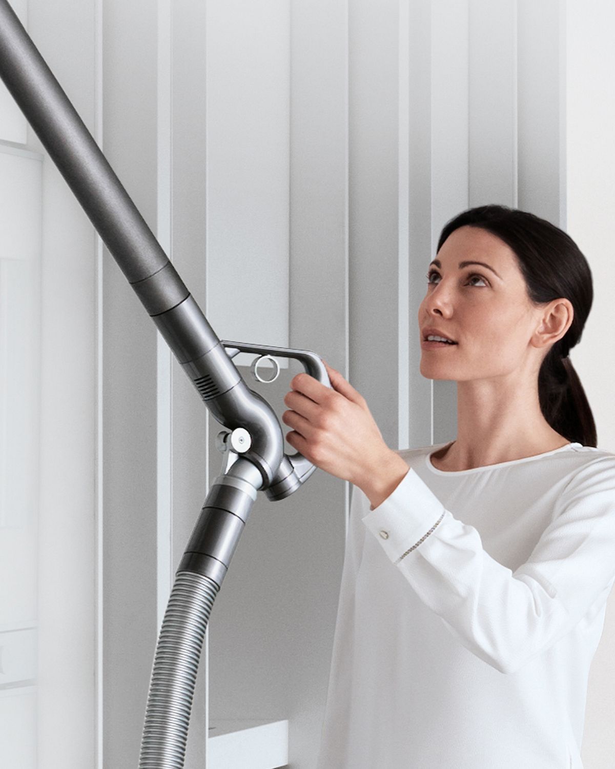Woman using extendable hose to clean hard to reach area. 
