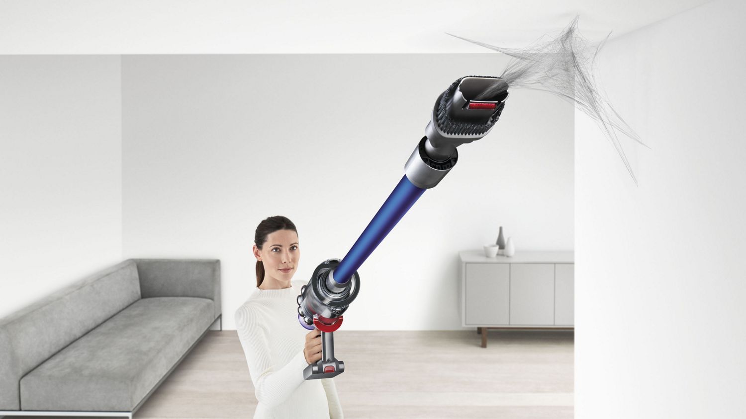 A Dyson V11 Torque Drive cordless vacuum cleaner removing cobwebs from a hard-to-reach spot on the ceiling