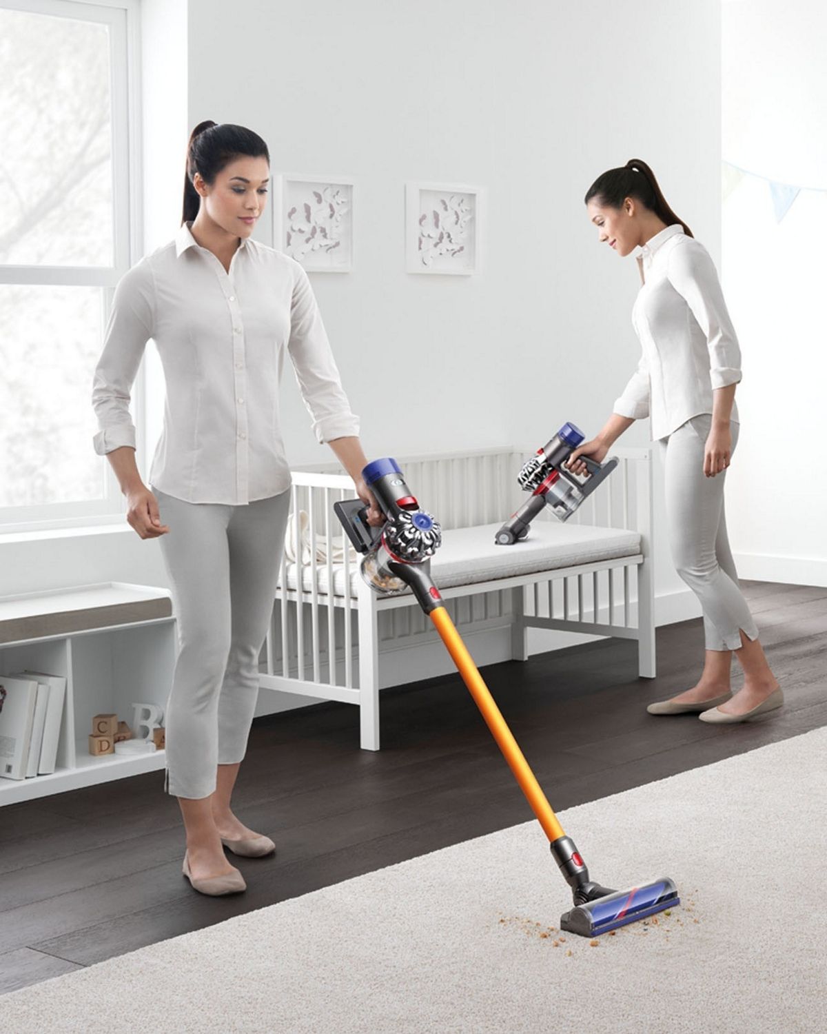 Time lapse effect image as a woman picks up debris from a carpet with a Dyson V8 Absolute cordless vacuum cleaner. The Dyson V8 Absolute cordless vacuum cleaner is also used in handheld mode to clean a set of shelves, a babies’ cot and pram.
